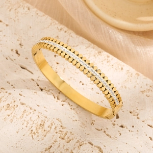 Elegant gold double-row studded bangle with pavé crystals on a textured travertine base