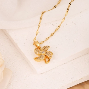 Golden rotating clover windmill pendant necklace with sparkling zircons on white stone base