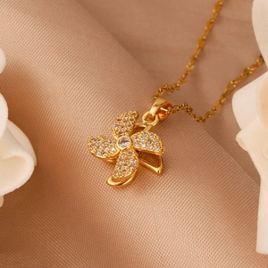 Golden rotating windmill necklace with sparkling white zircons on champagne silk fabric