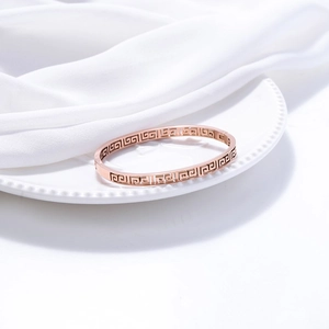 Detail of rose gold titanium cuff featuring intricate Greek key cutout patterns
