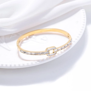 Bracelet jonc doré élégant avec zircons rectangulaires sur une assiette en céramique