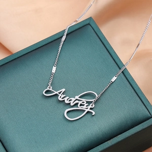 Custom silver titanium steel name necklace featuring Audrey pendant on green jewelry box
