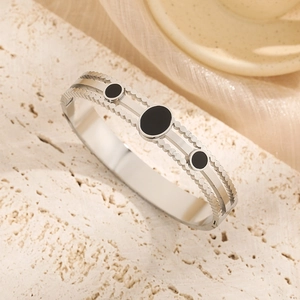 Silver stainless steel bangle with three black round stones and wavy gear edge design