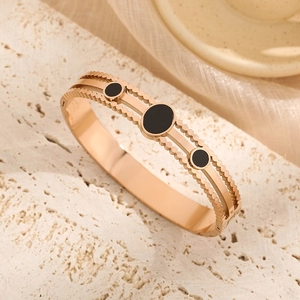 Rose gold titanium steel hollow cuff bracelet with black circular inlay on stone surface