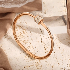Rose gold stainless steel bracelet with three sliding rhinestone rings on travertine base