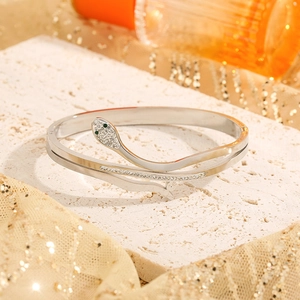 Elegant silver snake ring with green stone eyes and zircon paving on a stone base