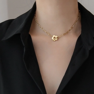 Detail of gold flower OT toggle clasp on rectangular link chain worn by a model