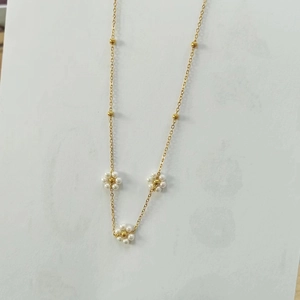 Detailed macro view of golden chain necklace with elegant white pearl flower pendants