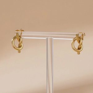Minimalist gold knot earrings with spiral twist design displayed on a T-bar stand