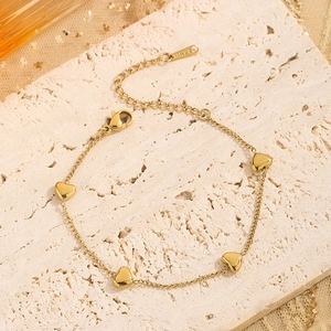 Close-up of gold heart charm bracelet in stainless steel with lobster clasp detail