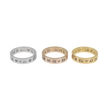 Close-up of stainless steel rings in silver, gold, and rose gold with Roman numerals