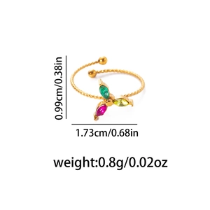 Bague ouverte torsadée dorée avec des pierres colorées en forme de trèfle sur fond blanc