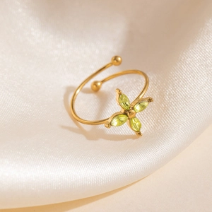 Bague ouverte dorée avec pétales de trèfle vert olive sur fond en soie lisse