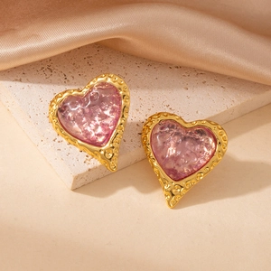 Primer plano de pendientes de corazón con resina rosa y textura de metal dorado martillado