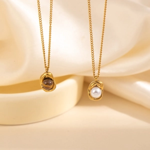 Detail of gold necklaces with molten lava pendants featuring white pearl and tiger eye stone