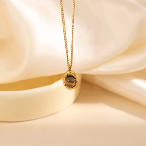 Detail of gold lava-style necklace featuring a striped tiger eye stone on silk fabric