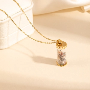 Detail of gold stainless steel necklace with a glass tube pendant filled with natural stones