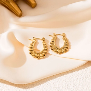 Détail de boucles d'oreilles dorées en U avec texture coquille et petit cœur