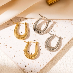 Detailed view of U-shaped twisted metal hoop earrings in polished gold and silver finishes