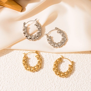 Détail de boucles d'oreilles créoles or et argent sur satin montrant la texture 3D