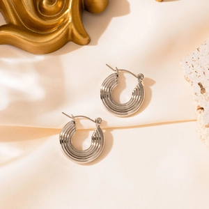 Vue détaillée de boucles d'oreilles argentées en C avec texture métal nervurée