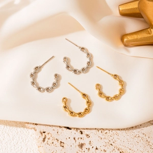 Detail of C-shaped chain-link earrings in gold and silver finish on silk background