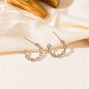 Polished silver chain texture C-shaped hoop earrings on elegant cream satin backdrop