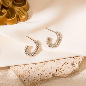 Macro view of silver twisted rope textured C-shaped hoop earrings on white satin