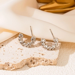 Detailed view of silver C-shaped earrings with embossed heart pattern on stone and silk