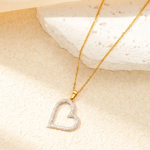 Close-up of golden heart-shaped necklace with paved stones on a natural stone base