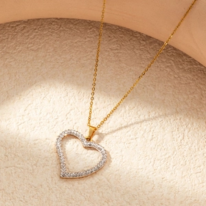 Close-up of heart-shaped gold necklace with sparkling crystals on textured surface
