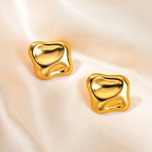 Detailopname van onregelmatige gouden lava-oorbellen op champagne zijden achtergrond