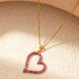 Macro detail of gold-plated hollow heart pendant necklace with pink zircon accents