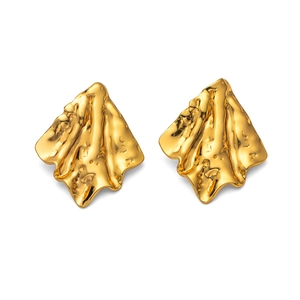 Macro detail van gouden onregelmatige geometrische oorbellen met lavastructuur en glans