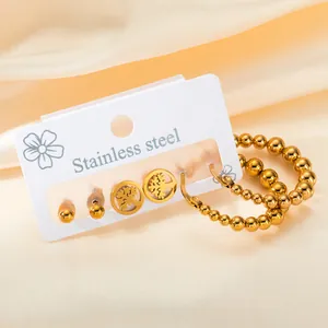 Minimalist golden stainless steel earring set featuring studs and beaded hoops on silk