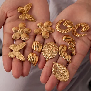 Details von handgehaltenen goldenen Titanstahl Ohrsteckern mit Schmetterling und Blatt