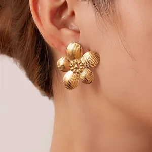Detailaufnahme eines 18K vergoldeten Blumenohrsteckers mit Textur an einem Modell