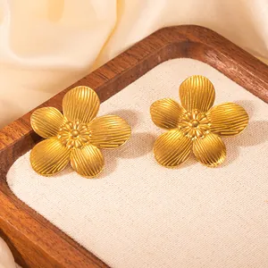 Detailaufnahme goldener Blütenohrringe mit gebürsteter Metallstruktur und 18K Gold-Finish