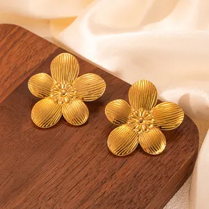 Makro-Detail goldener Blumen-Ohrstecker mit geschnitzter Textur auf Holz-Display