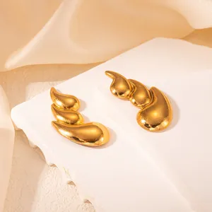 Detail von eleganten geschichteten Tropfenohrsteckern aus Gold auf Marmorsockel