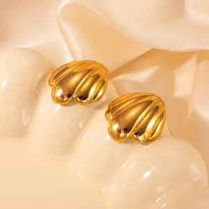 Nahaufnahme eleganter goldener Muschelohrstecker mit realistischer Textur auf Keramiktablett