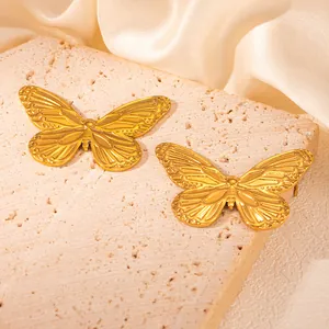 Detailansicht eleganter goldener Schmetterlingsohrringe mit feiner Flügelstruktur auf Stein