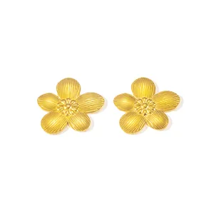 Nahaufnahme goldener Blumenohrstecker mit detaillierter Blütenblatt-Textur und Metallglanz