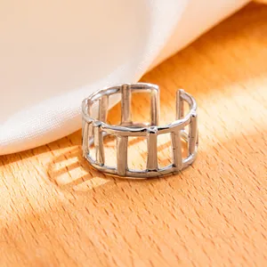 Dettaglio macro di anello geometrico traforato argento su superficie in legno