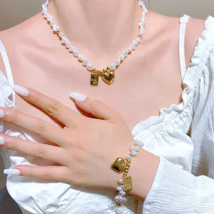 Detalle de collar de perlas barrocas y pulsera de corazón Good Luck puesto en modelo