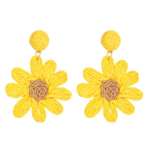 Detailed close-up of woven raffia sunflower earrings with yellow petals and brown center