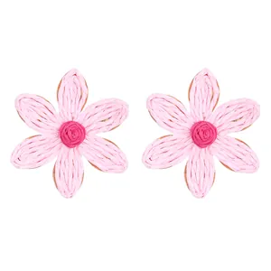 Macro view of woven pink raffia flower earrings with a layered petal design and texture