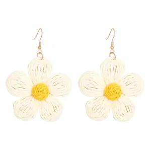 Detail of woven raffia flower earrings in yellow and cream with gold fishhooks
