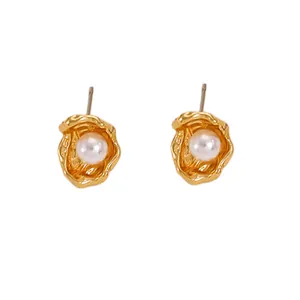 Detailed close-up of vintage golden baroque stud earrings with white pearl accents