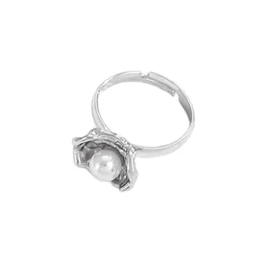 Detailed top view of a silver-toned open ring with flower texture and central white pearl